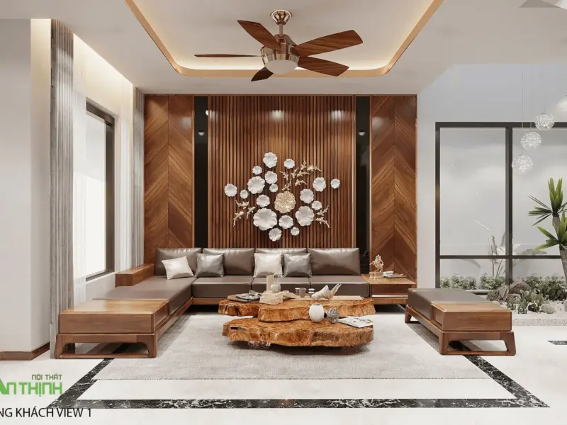 Phòng khách nhìn vào tường chính – bộ sofa góc gỗ óc chó nệm da xám, bàn trà gỗ nguyên khối hình tự do, hoa sắt trắng vàng, vách lát dọc vân xương cá