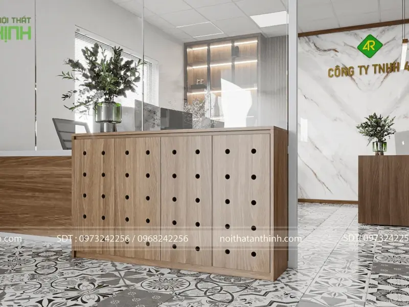 Quầy lễ tân – tủ quầy gỗ thiết kế lỗ tròn độc đáo, logo công ty trên đá marble phía sau, cây xanh trang trí, sàn gạch bông