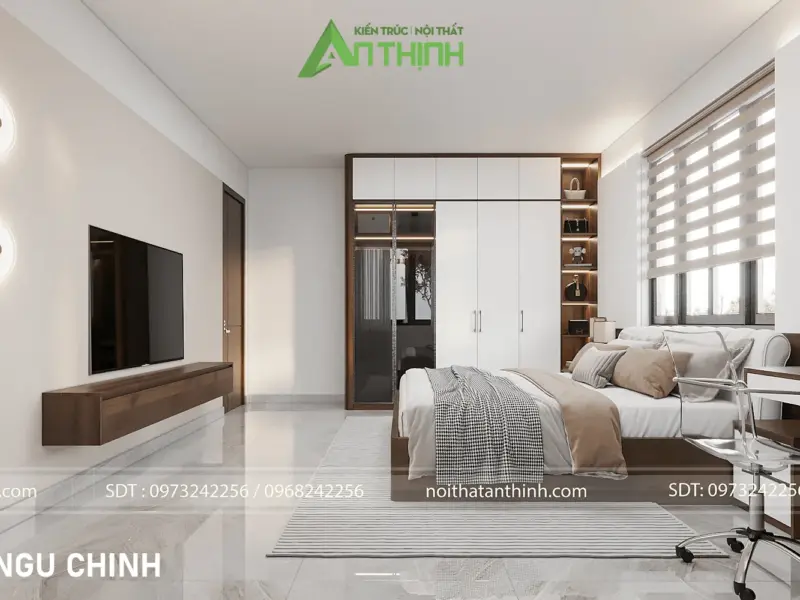 Toàn cảnh phòng ngủ chính – kệ tivi gỗ nổi trên tường, tủ kết hợp kệ trang trí mở có đèn spotlight, bàn làm việc riêng, rèm vải trắng nhẹ
