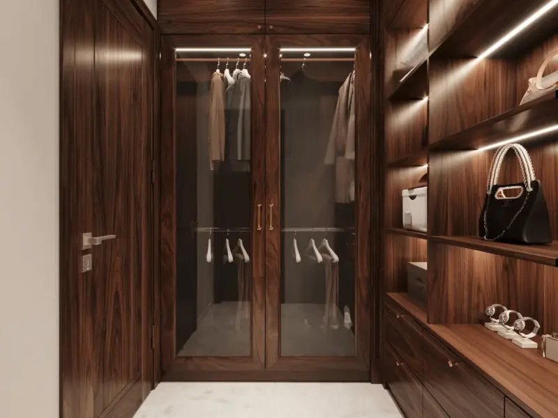 Walk-in closet góc treo quần áo – tủ kính cánh đôi khung vàng đồng, kệ gỗ óc chó trưng bày túi hàng hiệu, đèn LED spot chiếu sáng từng ô